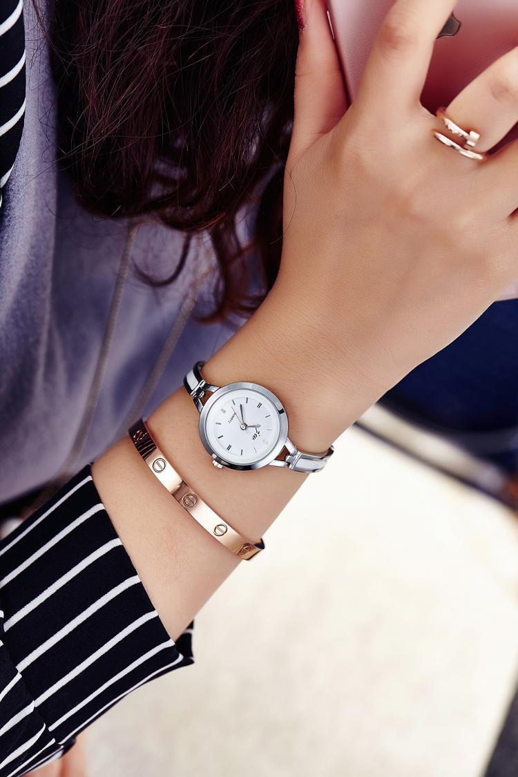 Close-up of a wrist wearing a silver watch with a blurred background