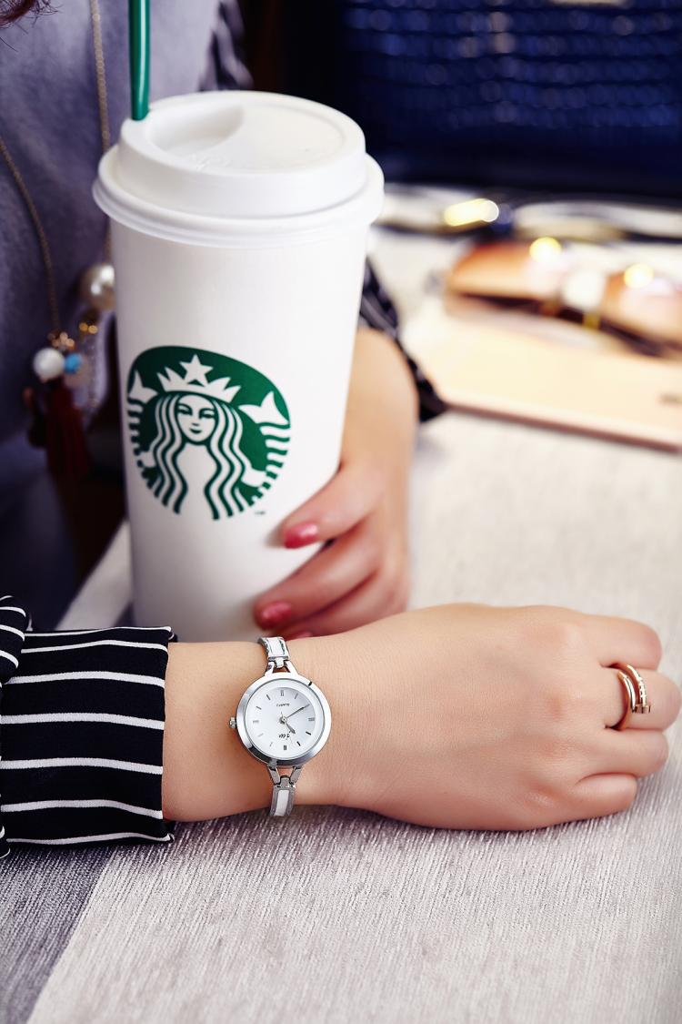 Person holding a Starbucks cup with a watch on wrist