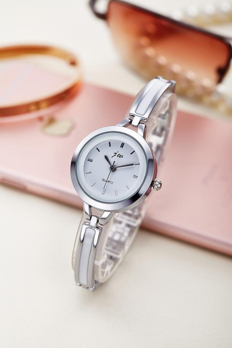 Silver wristwatch with white face on a light surface