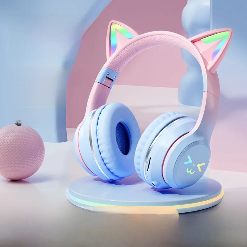 Pink and blue headphones with cat ears on a stand against a light background