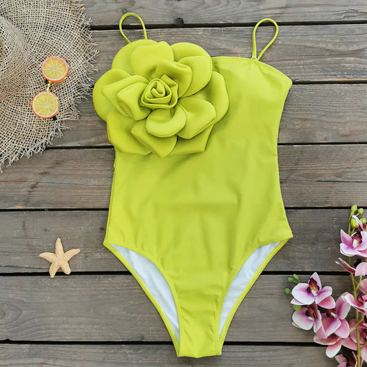 Yellow swimsuit with floral design on a wooden surface with decorative items.